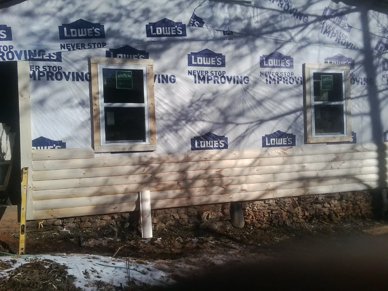 House wrap and new log siding going up on an exterior wall in Cohocton