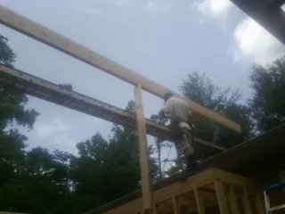 Carpenter setting a ridge beam over a new addition frame — Ice Dam Removal by Roofing Brothers in Cohocton