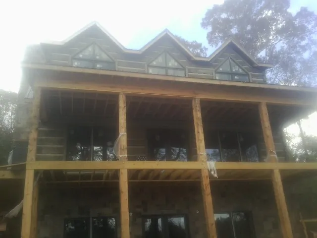 Dormers and porch framing on a large log home under construction — Roof Coating work by our crew in Cohocton