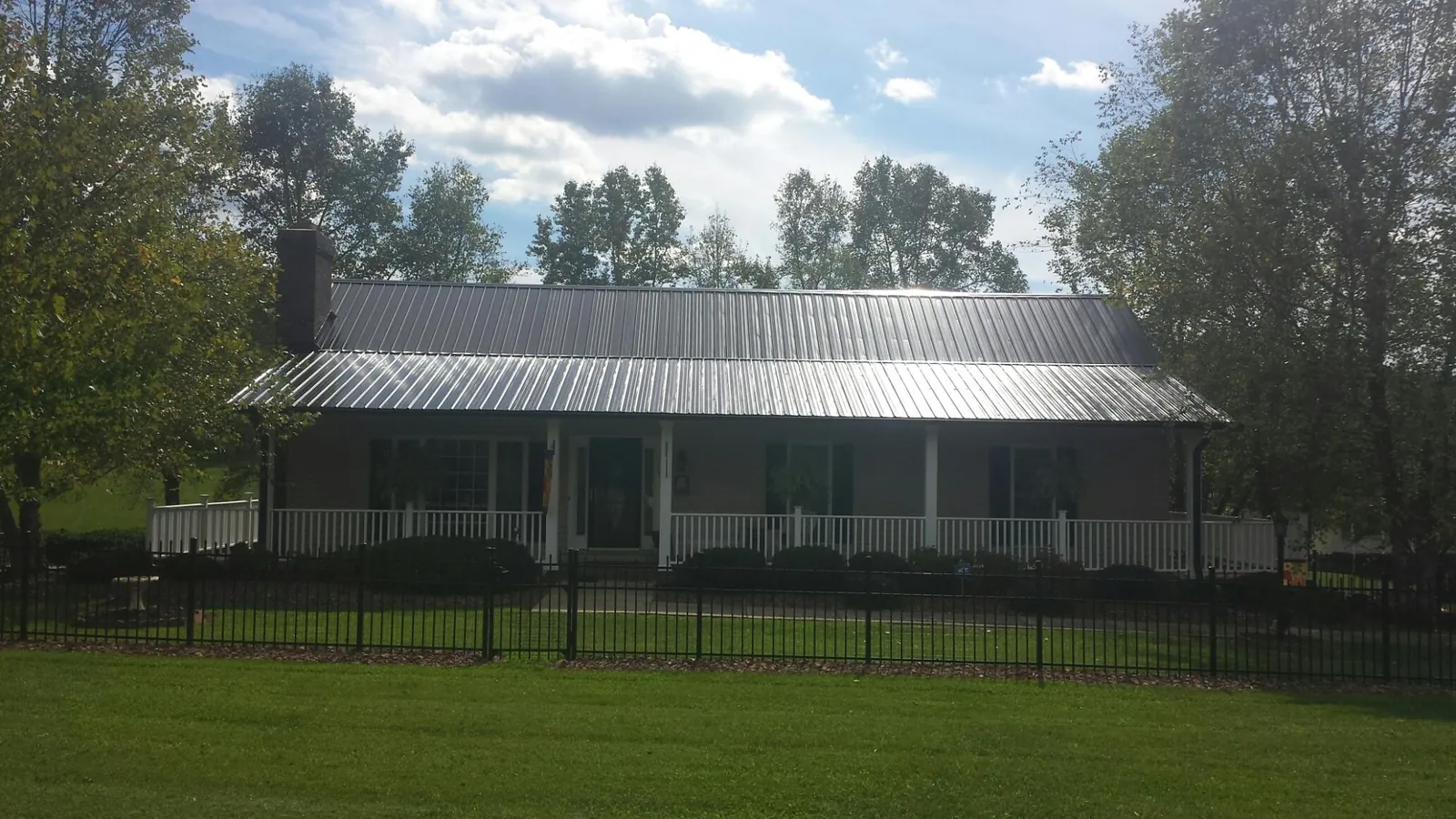Gray metal roof on a brick ranch with a full width front porch — Gutter Guard Installation work by our crew in Cohocton